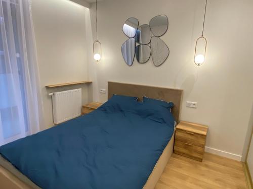 a bedroom with a blue bed and two mirrors on the wall at Apartament Pastelowy Kraków in Kraków