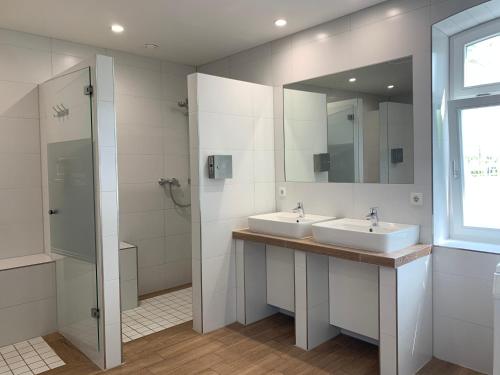 La salle de bains est pourvue de 2 lavabos, d'une douche et d'un miroir. dans l'établissement Outdoor Lounge am Belauer See mit Seezugang, à Belau