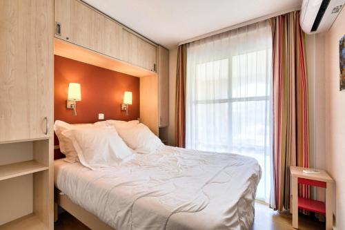 une chambre avec un grand lit et une fenêtre dans l'établissement Résidence le Village de Cap Esterel - maeva Home - Appartement 2 pièces 4 personnes - Prestige MAE-2644, à Saint-Raphaël