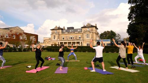 a group of people doing yoga in front of a house at Down Hall Hotel in Bishops Stortford