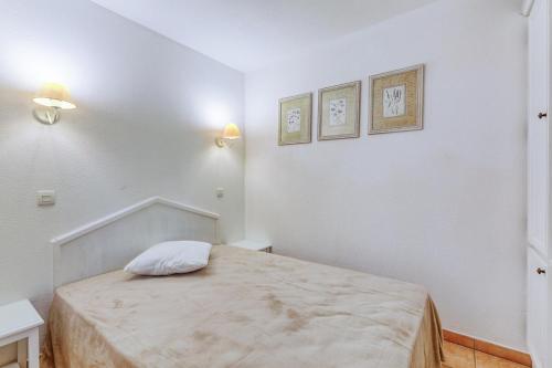 Cette chambre blanche dispose d'un lit et de deux photos sur le mur. dans l'établissement Résidence le Hameau des Issambres - maeva Home - Appartement 2 pièces 6 personnes - Confort MAE-1214, aux Issambres