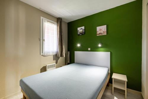 - une chambre verte avec un lit et une chaise dans l'établissement Résidence le Hameau de Cap Esterel - maeva Home - Appartement 3 pièces 6 personnes - Prestige MAE-1574, à Saint-Raphaël