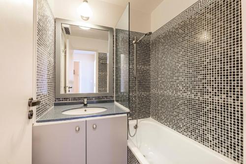 a bathroom with a sink and a mirror and a tub at Résidence le Hameau de Cap Esterel - maeva Home - Appartement 3 pièces 6 p 574 in Saint-Raphaël