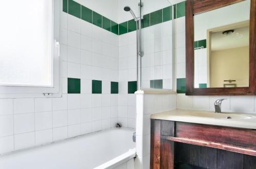 łazienka z wanną, umywalką i lustrem w obiekcie Les Maisons du Domaine du Golf de Pinsolle - maeva Home - Maison 3 pièces 6 personnes - Sélection MAE-9964 w mieście Soustons