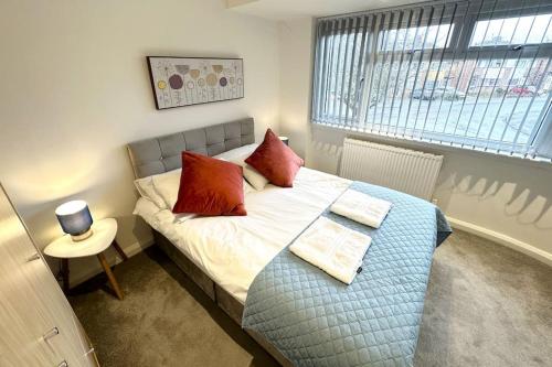a bedroom with a bed with red pillows and a window at Hazel 1-Bed Flat (3) + Parking in Kidlington
