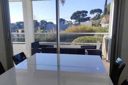 une table blanche et des chaises dans une pièce avec une fenêtre dans l'établissement SANARY - T2Bis sur Terrasse, à Sanary-sur-Mer