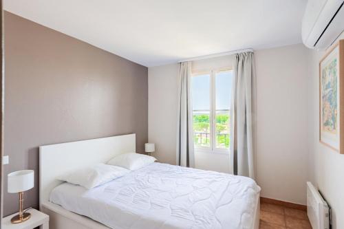a white bedroom with a bed and a window at Les maisons et villas de Pont Royal en Provence - maeva Home - Maison 4 piè 124 in Mallemort