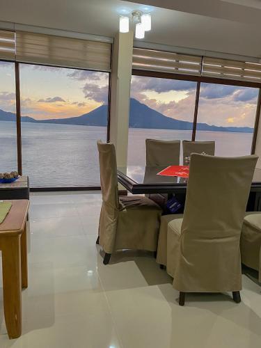 a dining room with a table and chairs and large windows at Torres de Atitlan 14 nivel in Panajachel