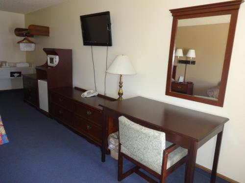 una camera d'albergo con scrivania e specchio di National 9 Inn a Garden City