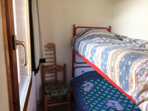 a bedroom with a bed and a chair next to a window at Résidence Plane - Studio pour 4 Personnes 574 in Montgenèvre