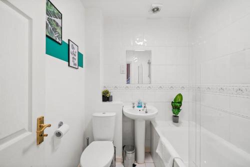 a white bathroom with a toilet and a sink at 4 Bedroom Cambridgeshire Home in Cambourne