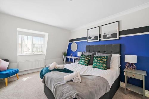 1 dormitorio con 1 cama grande y pared azul en 4 Bedroom Cambridgeshire Home, en Cambourne