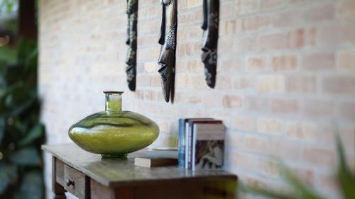 a green vase on a table next to a brick wall at Pousada Jeribá in Jericoacoara