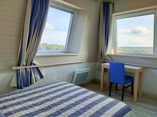 a bedroom with a bed and a desk and two windows at Hôtel le Littoral in Lézardrieux