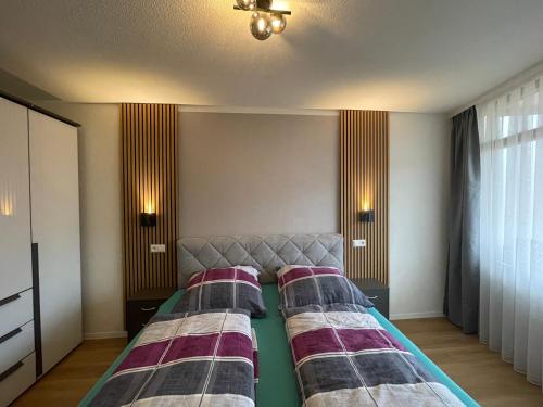 two beds in a room with two lamps on the wall at Ferienwohnung am Schluchsee in Schluchsee