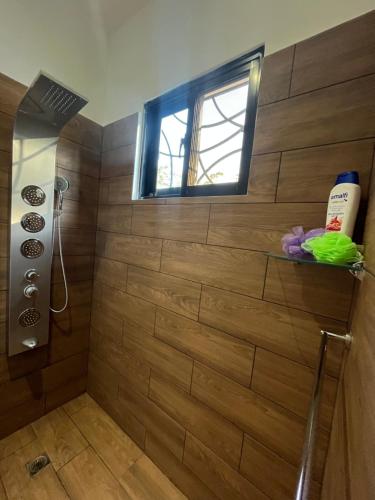 y baño con ducha y pared de madera. en Villa Achille, en Las Terrenas