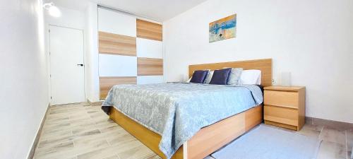 a bedroom with a bed with a blue blanket on it at National Trust Beach Apartment in Santiago del Teide