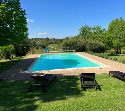 - une piscine avec 2 chaises dans l'herbe dans l'établissement Puyleger, à Saint-Privat-des-Prés