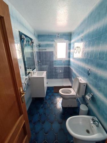 een blauw betegelde badkamer met een toilet en een wastafel bij Key Reig in Almussafes
