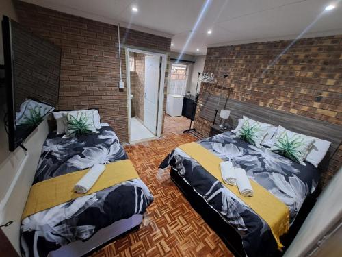 two beds in a room with a brick wall at Berlydai Guest Accomodation in Secunda