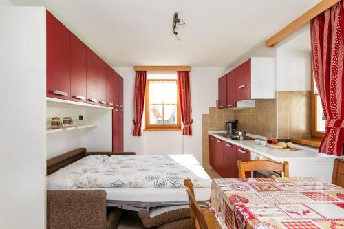 um pequeno quarto com uma cama e uma cozinha em Cesa Raggio di Sole Monolocale em Livinallongo del Col di Lana
