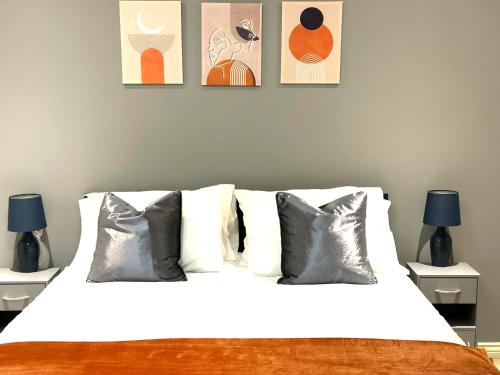 a bedroom with a white bed with three pictures on the wall at Margam's London Road Luxury Flat for Business Travellers, Relocator and Families with FREE Parking, High Speed Internet and fully equipped kitchen in Cheltenham