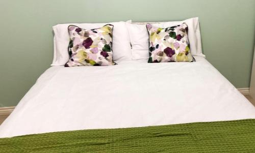 a white bed with two pillows on top of it at Margam's London Road Luxury Flat for Business Travellers, Relocator and Families with FREE Parking, High Speed Internet and fully equipped kitchen in Cheltenham