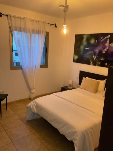 1 dormitorio con cama blanca y ventana en VV Princesa Guayarmina, en La Restinga