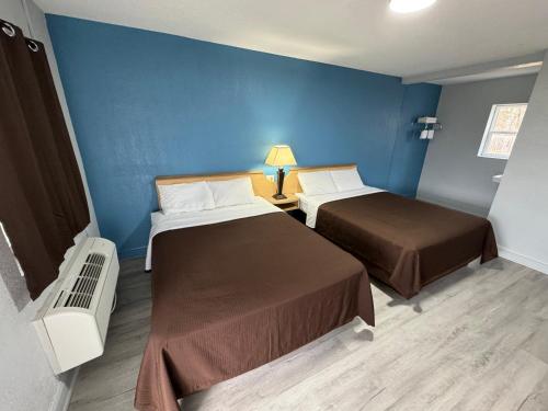 um quarto com duas camas e uma parede azul em Budget Inn em Thomasville