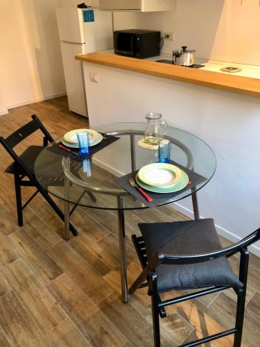 a glass table with two chairs and plates on it at Santa Giulia Suite - 15 minutes from city centre in Milan