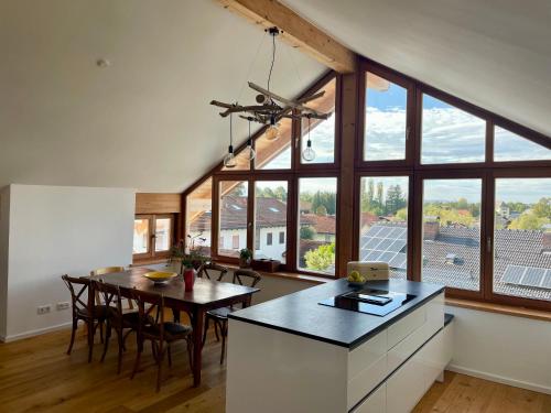希明格的住宿－Chiemsee Living，厨房以及带桌子和大窗户的用餐室。
