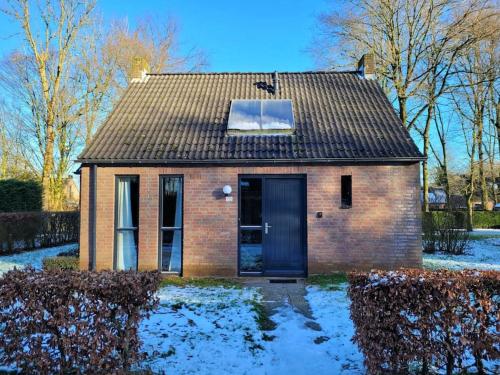 a small brick house with a black door in the snow at Japandi Wellness met hottub & sauna in Ewijk