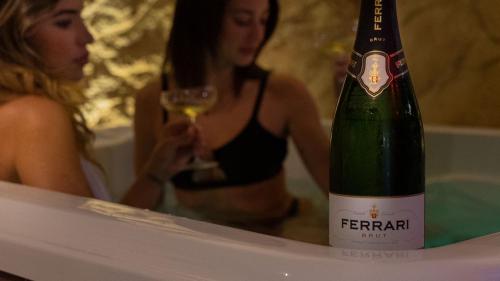 Eine Frau in einer Badewanne mit einer Flasche Champagner in der Unterkunft suite 43 in Terrasini