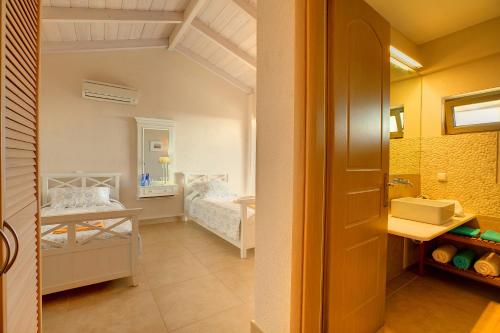 a small room with two beds and a bathroom at Villa Corali Ideales Resort in Kefallonia