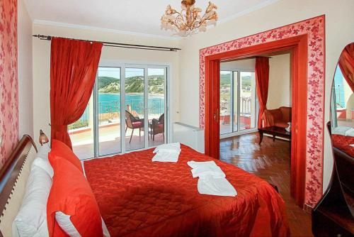 a bedroom with a red bed with a view of the ocean at Villa Romanza Beta in Agios Stefanos