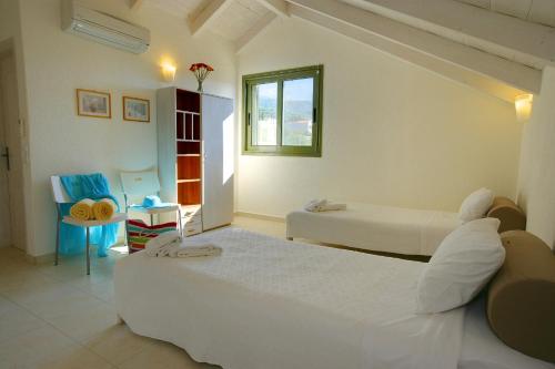 a bedroom with two beds and a table and a chair at Villa Petalida Ideales Resort in Kefallonia