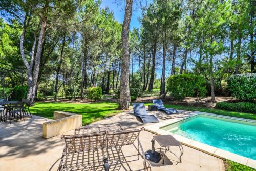 une cour avec une piscine, des chaises et une table dans l'établissement Les Mas et Villas de Pont Royal en Provence - maeva Home - Villa 5 Pièces 8 Personnes avec piscine privée et vue sur le golf - Exclusive - super Home MAE-6074, à Mallemort
