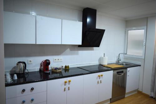 a kitchen with white cabinets and a black counter top at Piso cercano Plaza San Cayetano en Yecla in Yecla