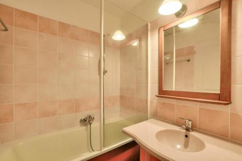 une salle de bain avec un lavabo, une baignoire et un miroir dans l'établissement La résidence du Lac - maeva Home - Appartement 2 pièces 5 personnes - Confort MAE-4184, à Monflanquin