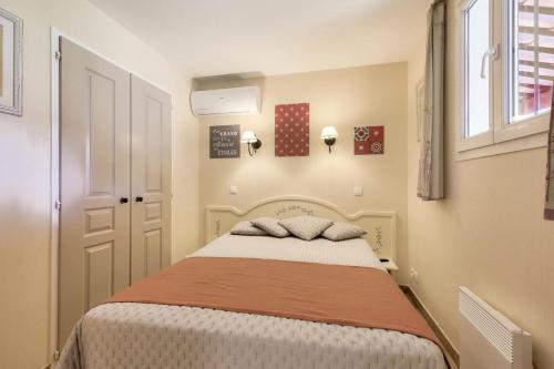 - une chambre dotée d'un lit avec une couverture orange et blanche dans l'établissement Les Appartements aux Restanques du Golfe de St Tropez - maeva Home - Appartement belle vue mer 3 pièces 7 personnes - Sélection MAE-1794, à Grimaud