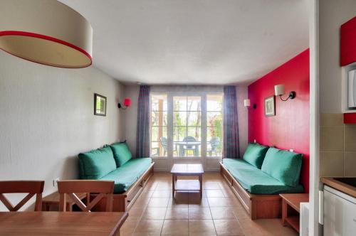 un salon avec des canapés verts et une table dans l'établissement La résidence du Lac - maeva Home - Studio 5 Personnes - Sélection MAE-4214, à Monflanquin