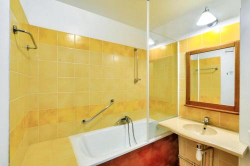 une salle de bain avec une baignoire, un lavabo et un miroir dans l'établissement La résidence du Lac - maeva Home - Studio 5 Personnes - Sélection MAE-4214, à Monflanquin