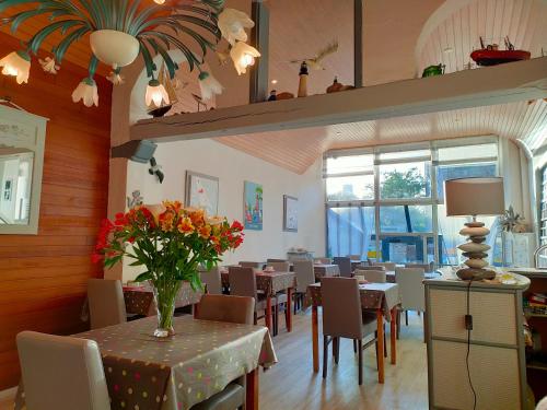 un restaurant avec des tables, des chaises et un vase de fleurs dans l'établissement Hôtel le Littoral, à Lézardrieux
