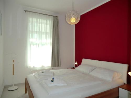 a bedroom with a white bed and a red wall at Leuchtturm - Whg1 in Wyk auf Föhr