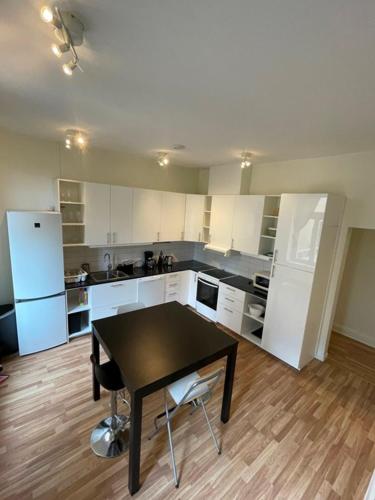 a kitchen with a table and a kitchen with white cabinets at Rentalux Apartments at Nybrogatan in Sundsvall