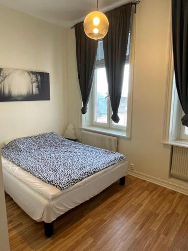 a bedroom with a bed and two windows at Rentalux Apartments at Nybrogatan in Sundsvall