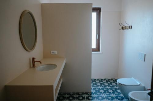 a bathroom with a sink and a toilet and a mirror at Adagio House in Valdamonte
