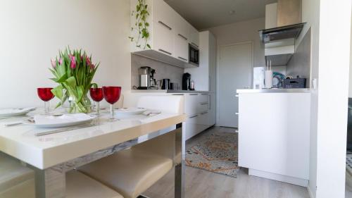 a white kitchen with red wine glasses and flowers on a counter at Spacious 68m2 apartment with fabulous forest view in Järvenpää