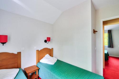 - une chambre avec 2 lits et un sol rouge dans l'établissement La résidence du Lac - maeva Home - Maison 3 pièces 6 personnes - Sélection MAE-5604, à Monflanquin