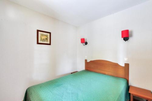 - une chambre avec un lit vert et deux lumières sur le mur dans l'établissement La résidence du Lac - maeva Home - Appartement 2 pièces 5 personnes - Sélection MAE-5524, à Monflanquin